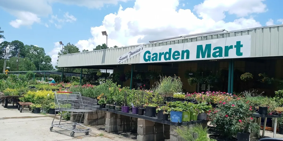 Family-owned garden center with vibrant displays of healthy plants, organized sections for mulch and fertilizers, and a...