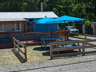 Clean ice cream shop with visible prep area, outdoor picnic tables under umbrellas, and a large menu board displaying...