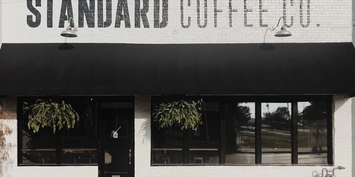 Stylish interior coffee shop with varied seating arrangements, local artwork on walls, and a serve-yourself water station...