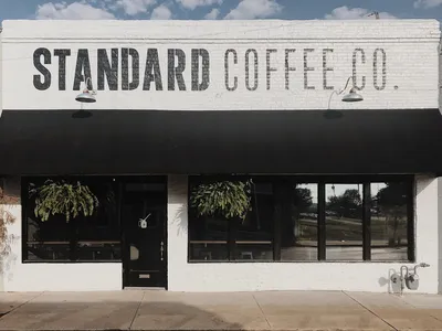 Stylish interior coffee shop with varied seating arrangements, local artwork on walls, and a serve-yourself water station...
