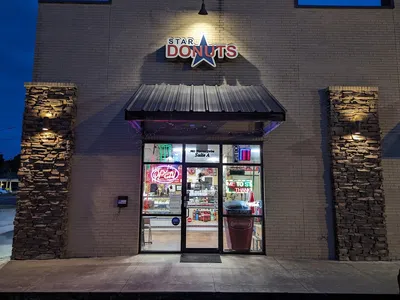 Cozy bakery counter displaying fresh glazed donuts, specialty kolaches, and beignets with outdoor seating area visible.