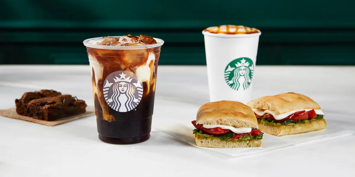 Modern Starbucks storefront with drive-through lane and outdoor seating area on Sterlington Road, frequented by students...
