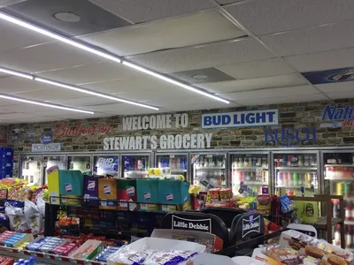 Neat, well-organized convenience store with a bustling deli counter and fresh seafood section, showing prepared food...