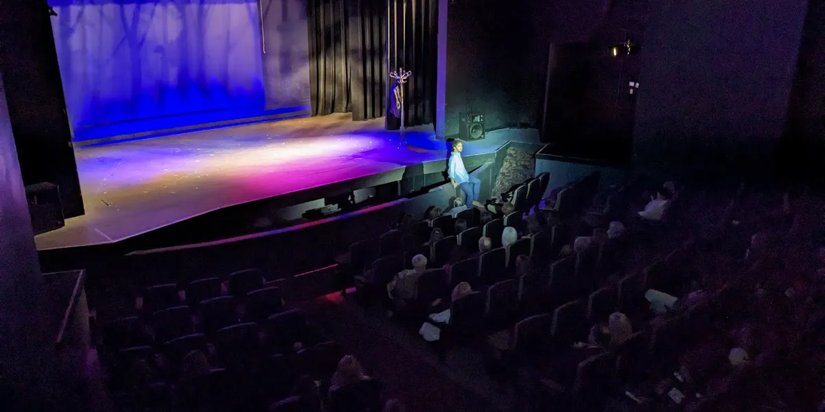 Intimate theater with new comfortable seating arranged before a well-lit stage, where local talent performs in a clean,...