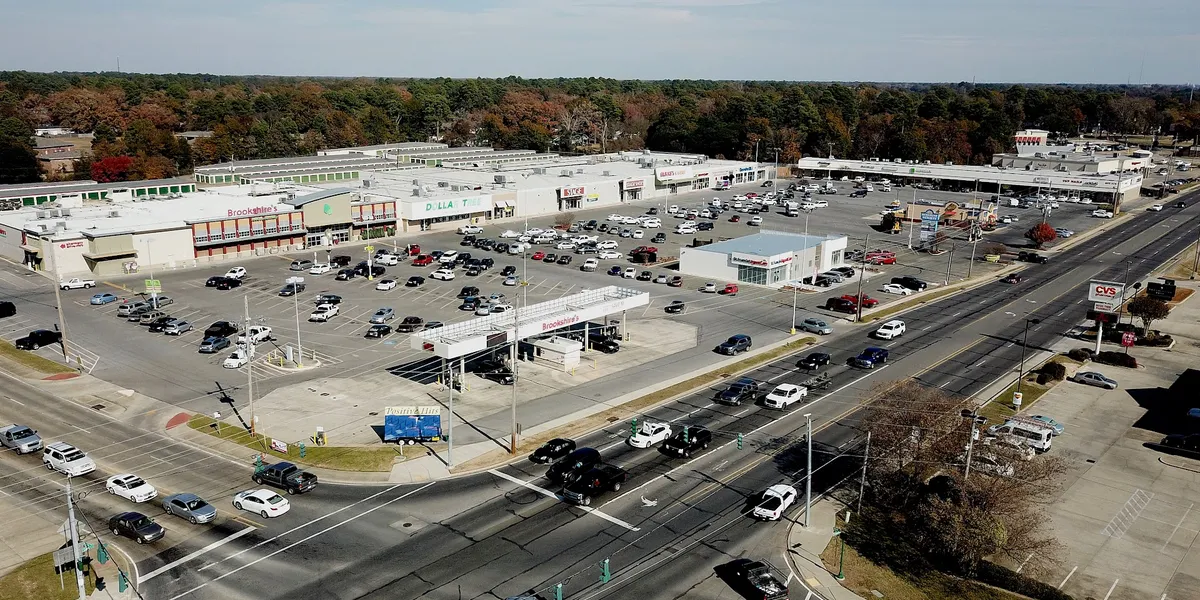Exterior view of Sunshine Heights shopping mall with multiple storefronts including Brookshire Foods and Russell's Hair...