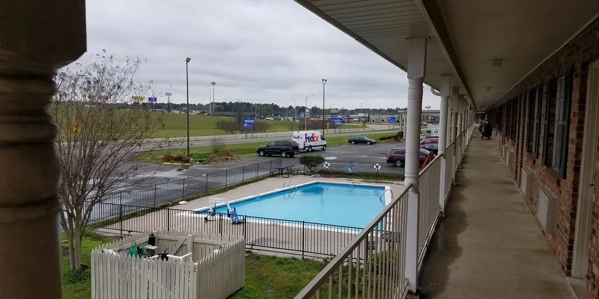 Exterior view of Super 8 motel with parking lot entrance doors, simple furnishings, and dated decor in a convenient...