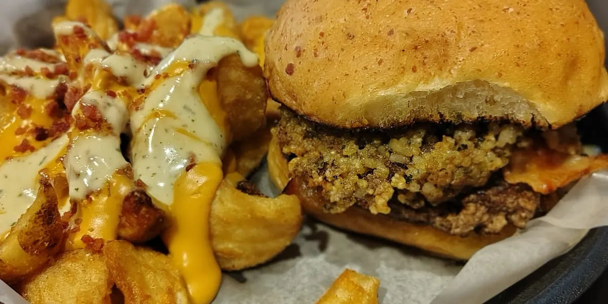 Riverside terrace at Tail Gators with tables overlooking the Ouachita River, local artwork on walls, and lively bar area...