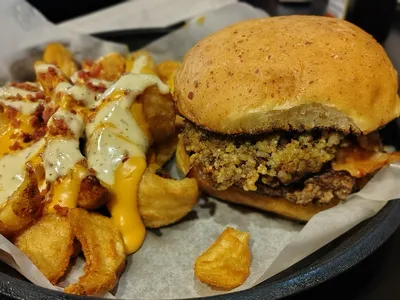 Riverside terrace at Tail Gators with tables overlooking the Ouachita River, local artwork on walls, and lively bar area...