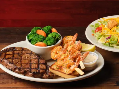 Rustic steak house interior with bar seating area where customers socialize, featuring wooden tables and country-western...