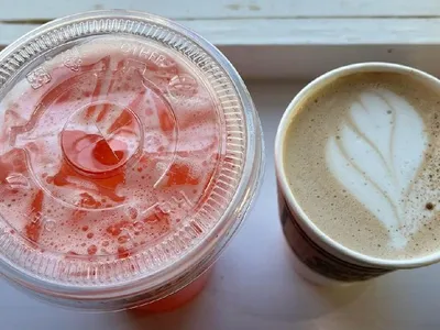 Intimate coffee shop with outdoor seating area where customers enjoy specialty drinks while dogs relax at their feet.