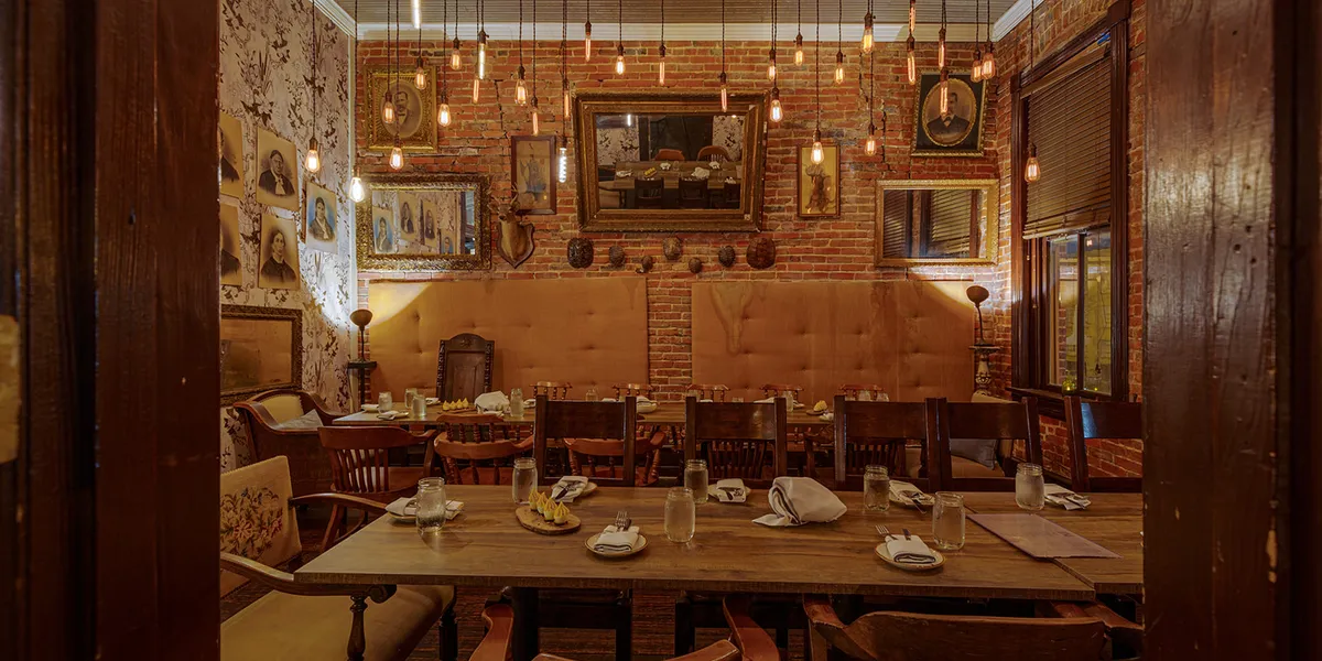 Intimate speakeasy-style bar with cozy wingback chairs, warm lighting, and a sophisticated cocktail service area in...