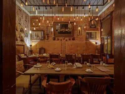 Intimate speakeasy-style bar with cozy wingback chairs, warm lighting, and a sophisticated cocktail service area in...
