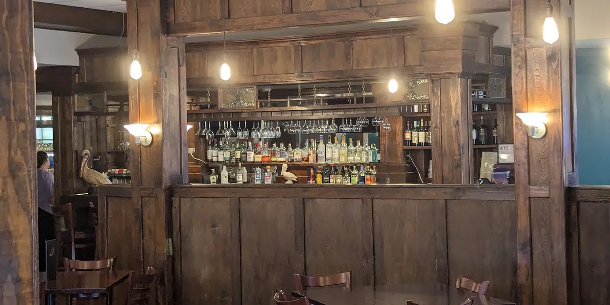 Elegant dining space at The Fat Pelican with carefully arranged tables, subtle lighting, and a sophisticated bar...