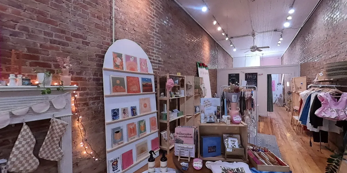 Bright, inviting gift shop with displays of handcrafted local goods, art pieces, and a workshop area for creative classes.
