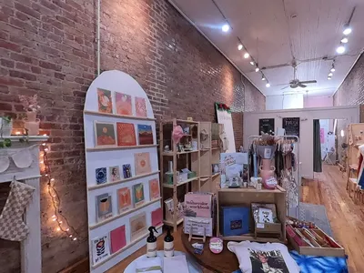 Bright, inviting gift shop with displays of handcrafted local goods, art pieces, and a workshop area for creative classes.