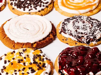 Bright, clean bakery counter displaying colorful cobblers and puddings with comfortable seating for families celebrating...