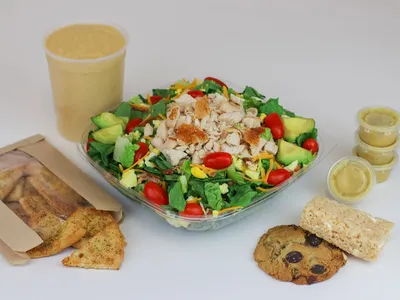 Bright, clean salad bar station with fresh ingredients displayed in neat rows, families selecting toppings at the counter.