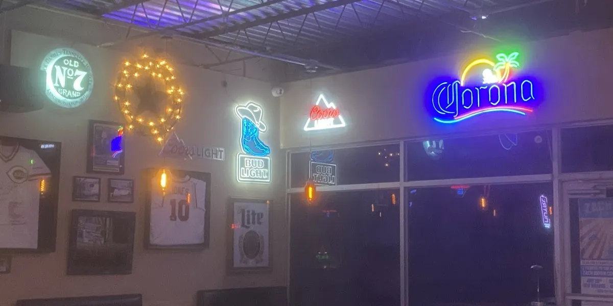 Bustling college bar with outdoor seating area, live music stage, and standing-room floor space where patrons gather for...