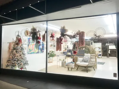 Bright boutique with displays of handcrafted glassware, original paintings, and eclectic jewelry arranged throughout a...