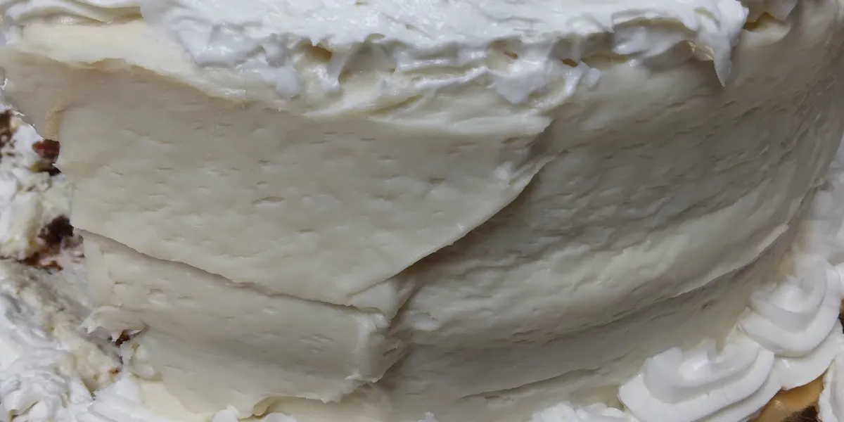 Cozy bakery counter displaying Italian Creme Cakes, wedding cake samples, and homestyle prepared dishes in a bright,...