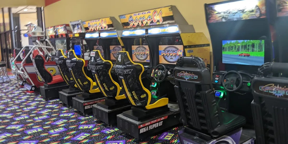 Expansive arcade floor with colorful gaming machines arranged in rows throughout a well-lit, indoor entertainment space...