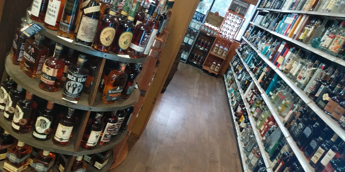 Well-stocked wine shelves at Tonore's featuring diverse bottles arranged by region, with a dedicated bourbon and spirits...