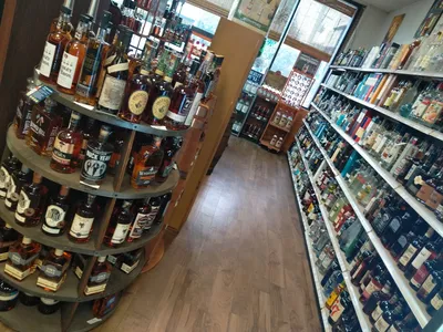 Well-stocked wine shelves at Tonore's featuring diverse bottles arranged by region, with a dedicated bourbon and spirits...