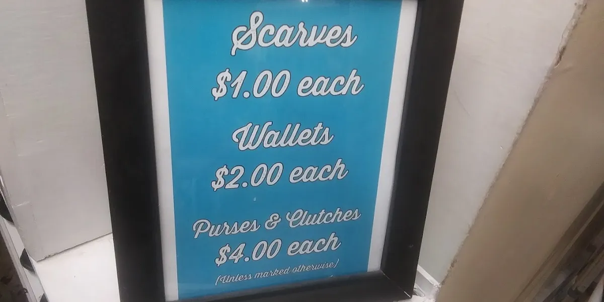 Bright, organized thrift store with neatly arranged sections, handcrafted faith items displayed prominently, and women...