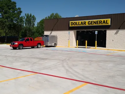 Neatly maintained mobile home community with freshly cut grass, parked trailers, and visible road damage at the entrance...