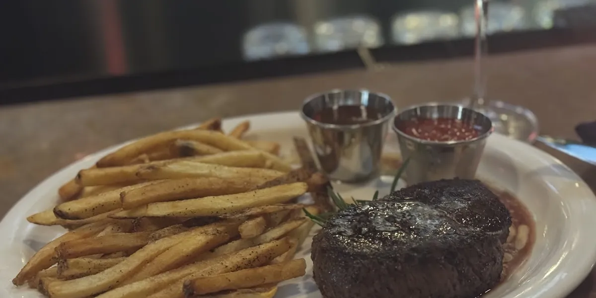 Cozy restaurant with low lighting, combining casual and elegant elements, featuring intimate seating and a well-stocked...