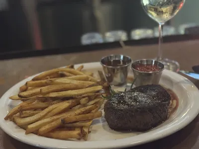 Cozy restaurant with low lighting, combining casual and elegant elements, featuring intimate seating and a well-stocked...