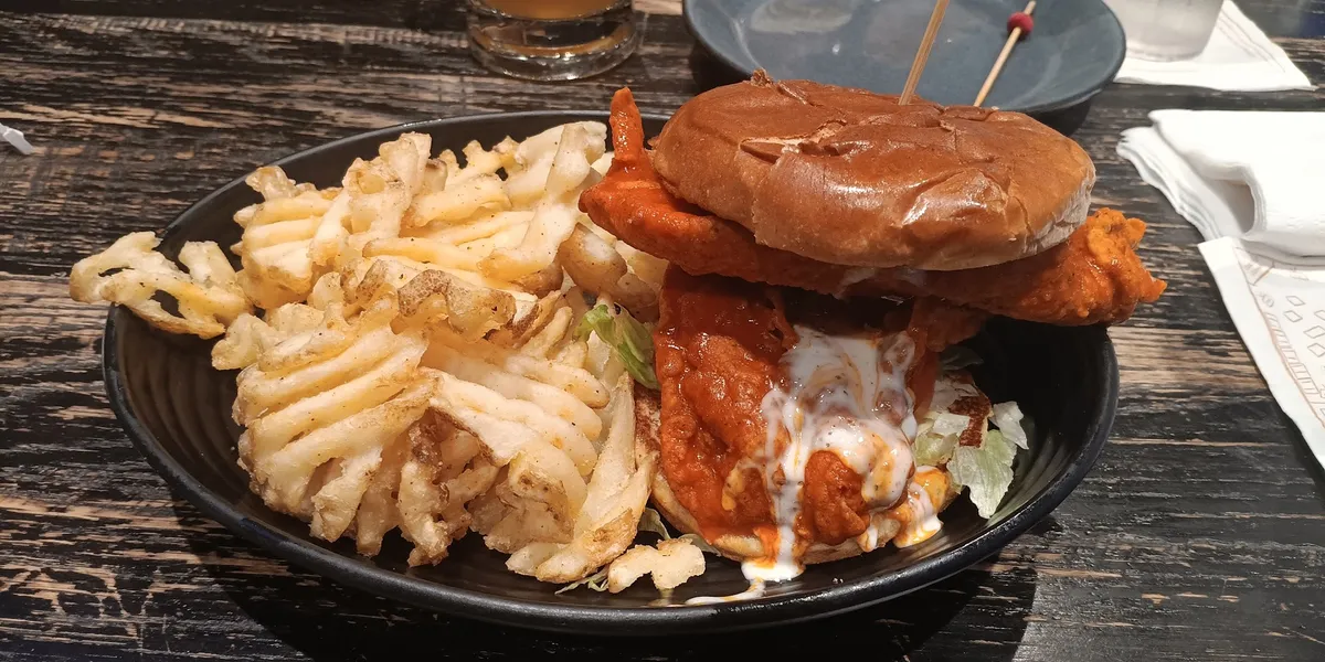 Spacious sports bistro with multiple TVs, bustling bar area, and comfortable dining sections filled with sports...