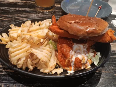 Spacious sports bistro with multiple TVs, bustling bar area, and comfortable dining sections filled with sports...