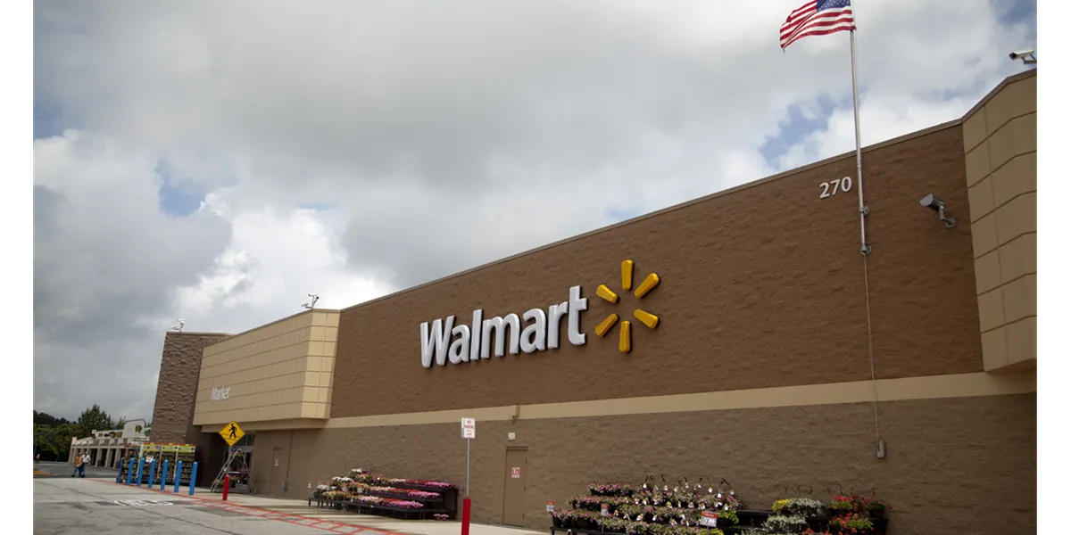 Expansive Walmart Supercenter with multiple wide entrances, bustling with shoppers navigating diverse merchandise sections.