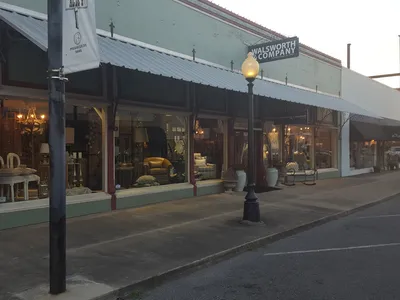 Newly remodeled showroom displaying high-end furniture pieces including solid burl wood dressers and genuine leather...