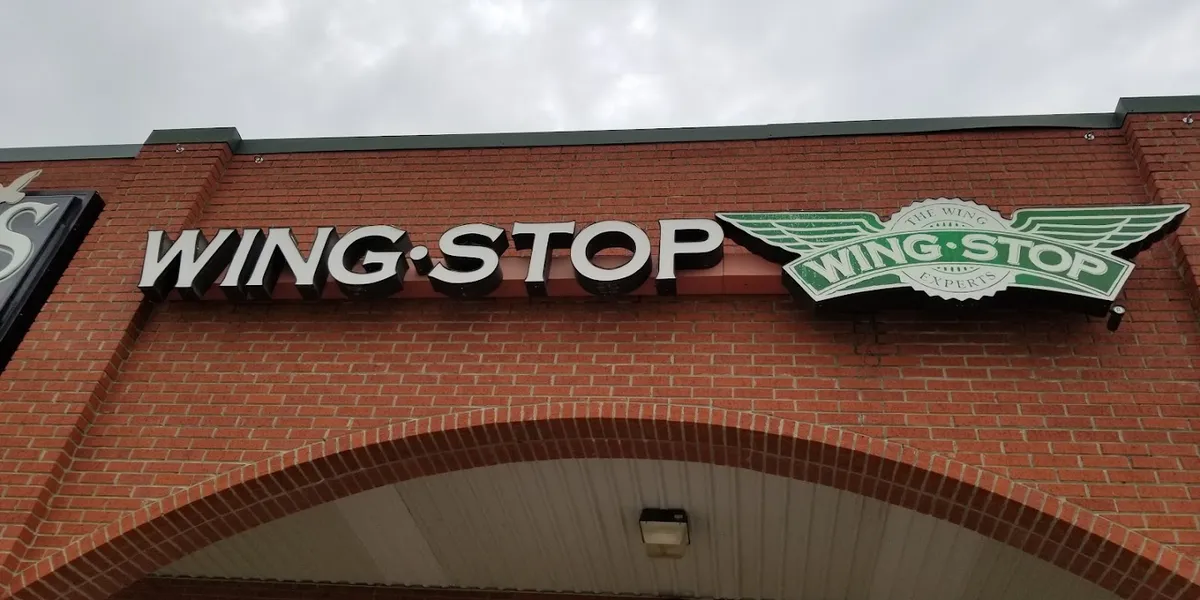 Counter-service wing restaurant with bright lighting and modern ordering system, busy during peak hours with customers...