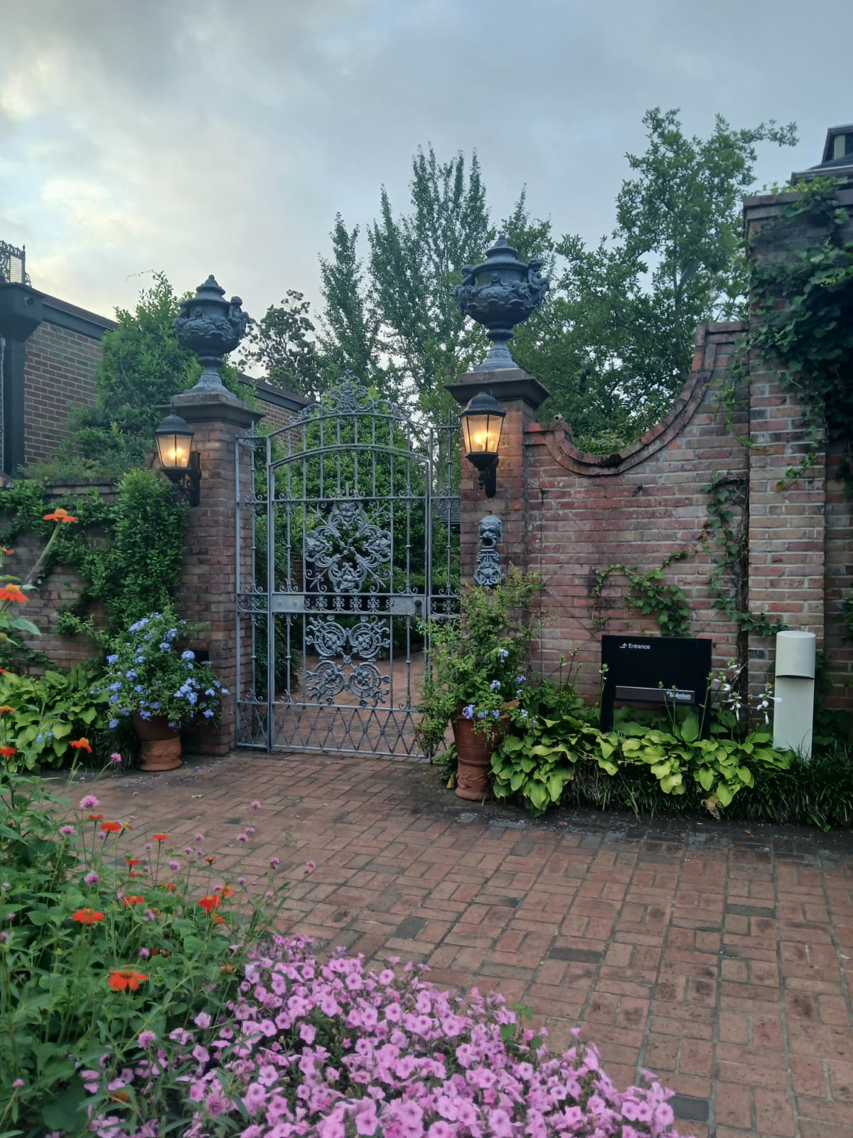 Ornate iron garden gate with lanterns and flowers at Elsong Gardens Biedenharn Museum Monroe Louisiana