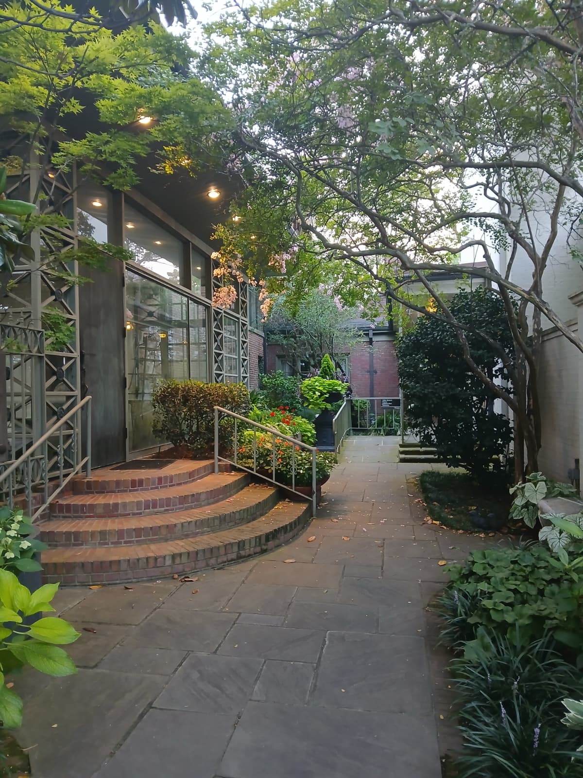 Stone walkway through Elsong Gardens at Biedenharn Museum Monroe Louisiana with lush greenery overhead