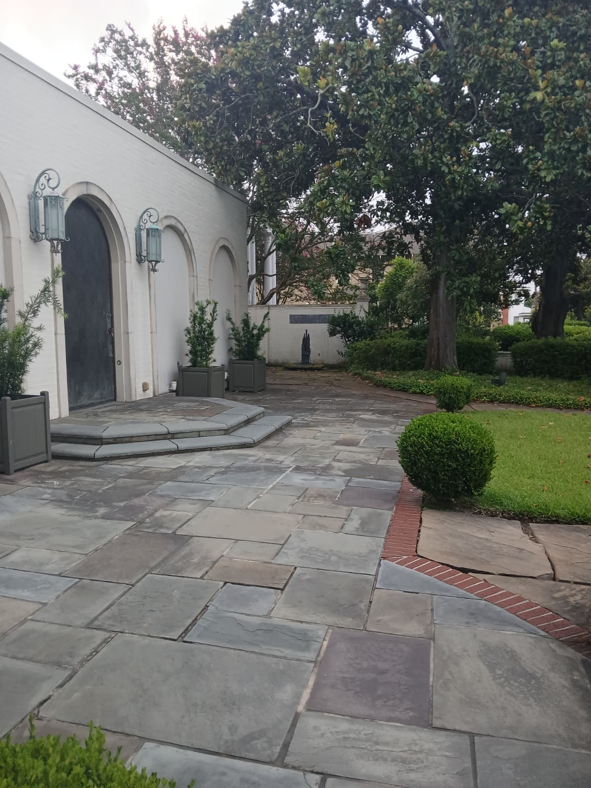 Stone courtyard with arched doors and iron lanterns at the Emy-Lou Biedenharn Recital Hall in Monroe Louisiana