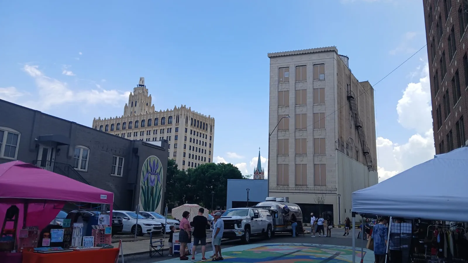 Art Alley in downtown Monroe during The Good Daze Block Party on July 4th 2026. Colorful ground mural, vendor tents, food truck, and historic buildings under a blue sky.