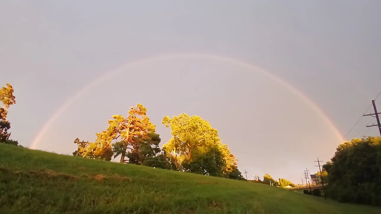 Double rainbow arching over the grassy levee in West Monroe, Louisiana on July 4th 2026, purple sky after rain