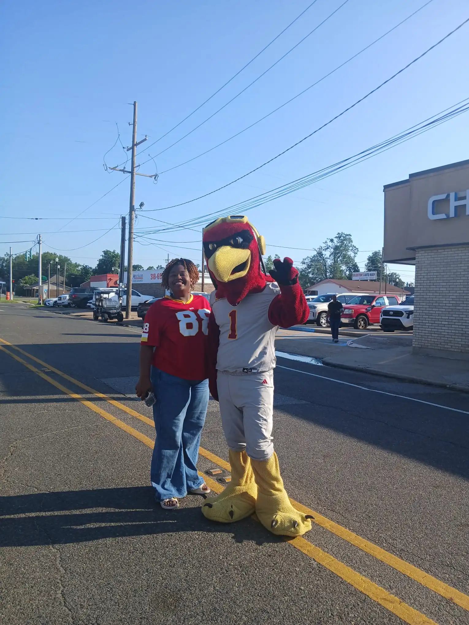 Red bird mascot posing with a race participant on DeSiard Street during the Fleet Feet Fourth of July Race in Monroe, Louisiana