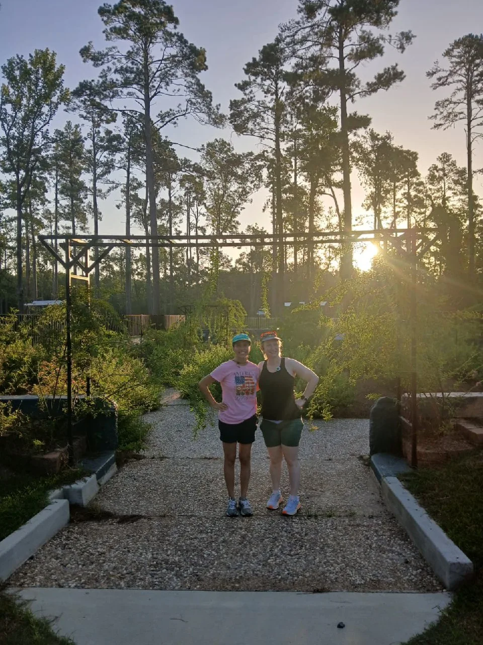Two people standing in the Sunken Garden at Kiroli Park, with sun rays breaking through the trees.