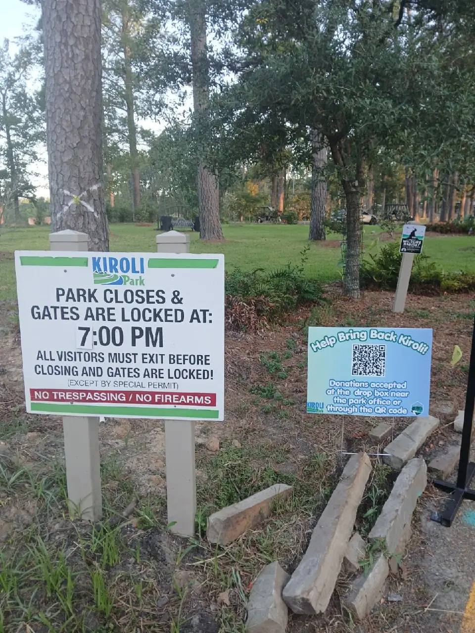 Park rules sign stating the park closes and gates are locked at 7 p.m., next to a donation QR code.