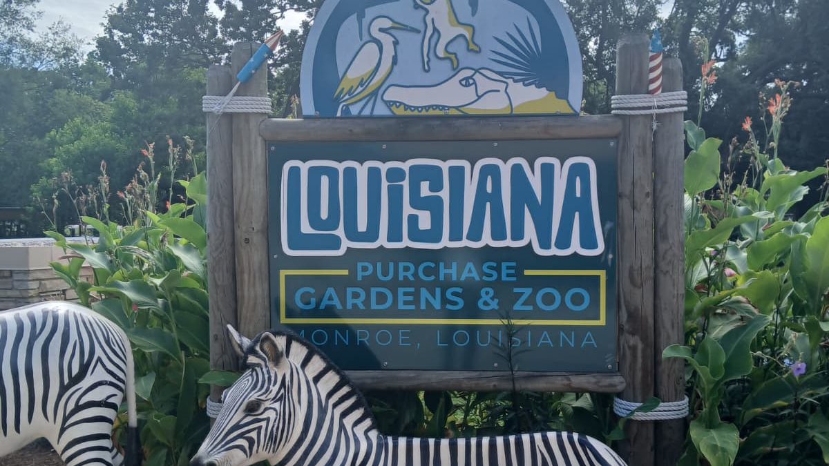 Louisiana Purchase Gardens and Zoo entrance sign in Monroe Louisiana with zebra statues and tropical plants