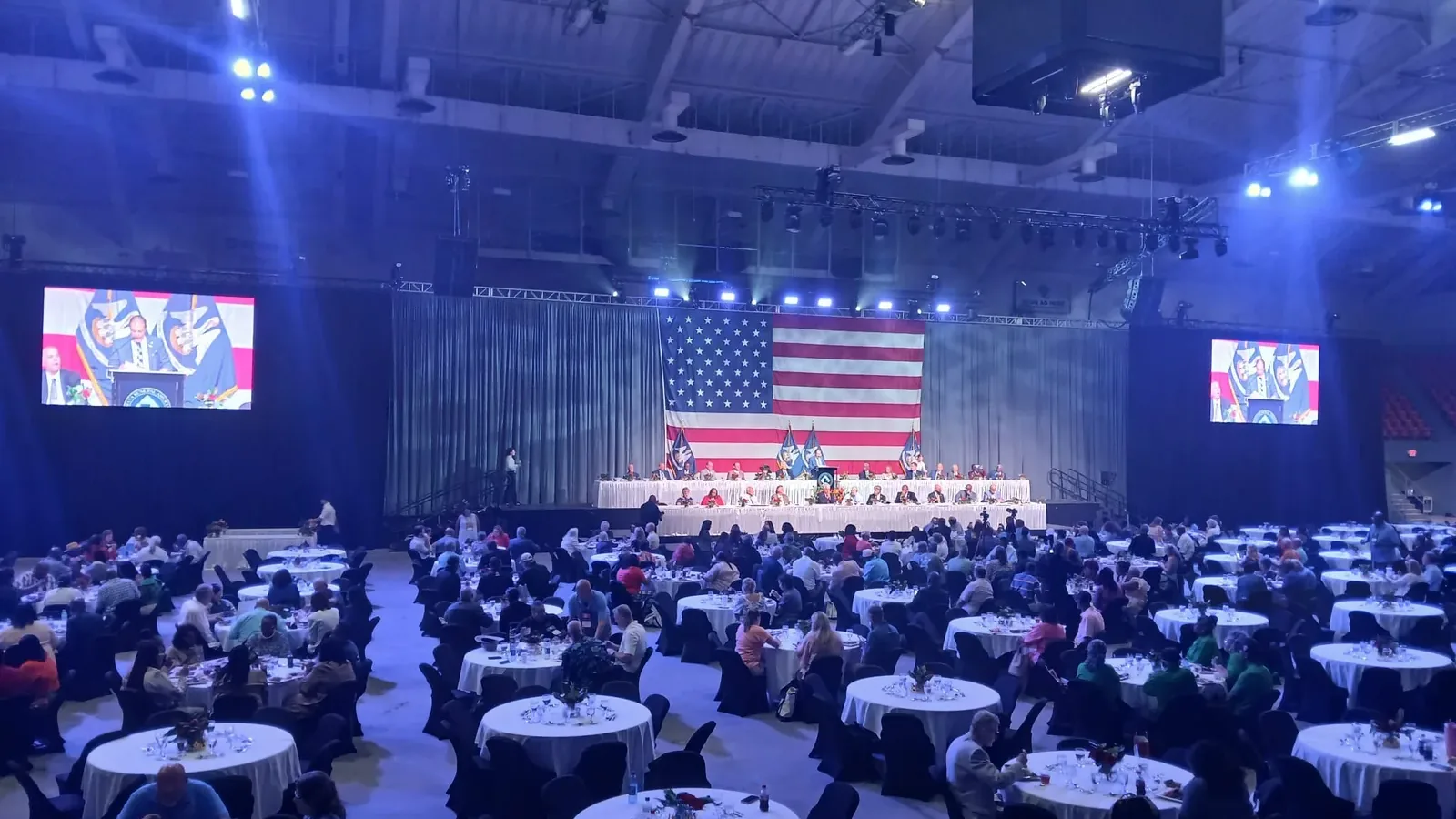 Wide shot of a large event hall at the Monroe Civic Center set up with round tables for a formal dinner.