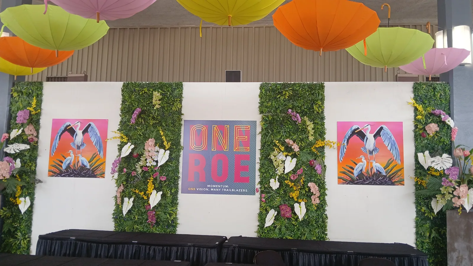 The ONE ROE event backdrop with heron artwork and floral decor at the LMA Convention in the Monroe Civic Center.
