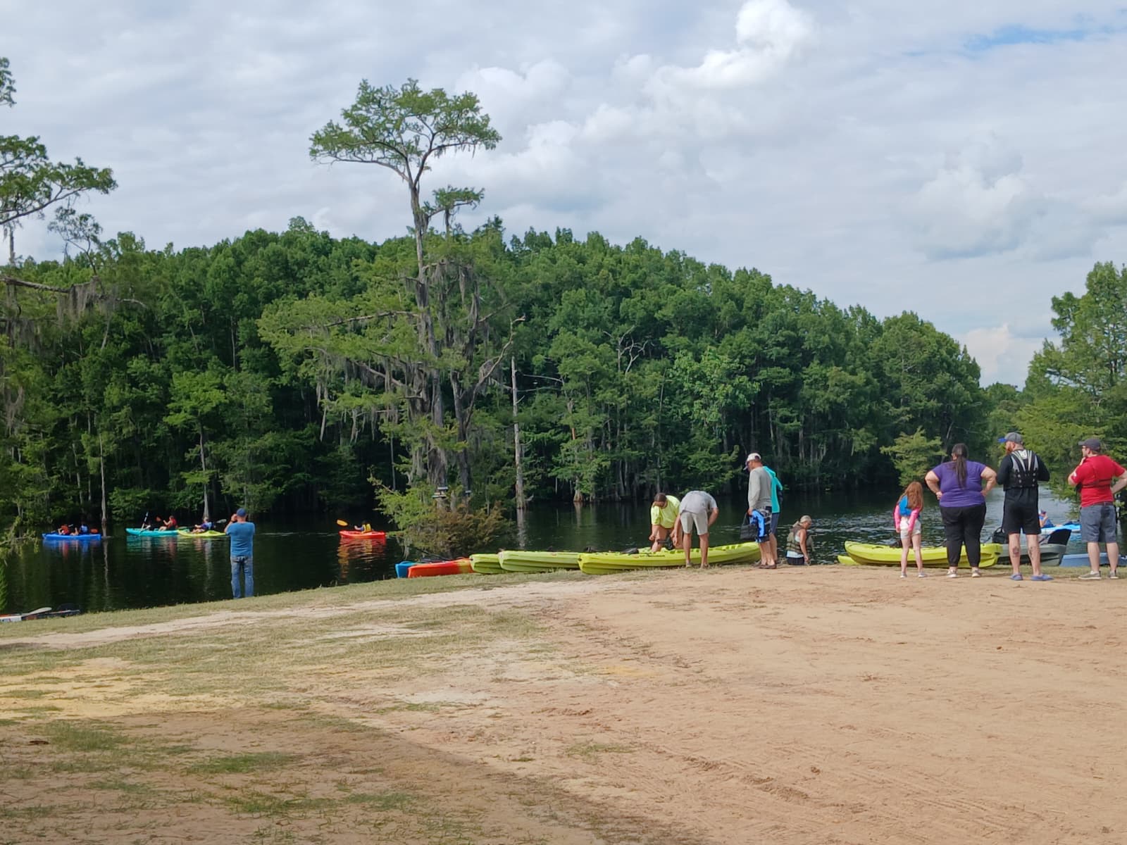 Colorful kayaks lined up on the sandy shore at Cheniere Lake Area 3, Ouachita Parish Louisiana