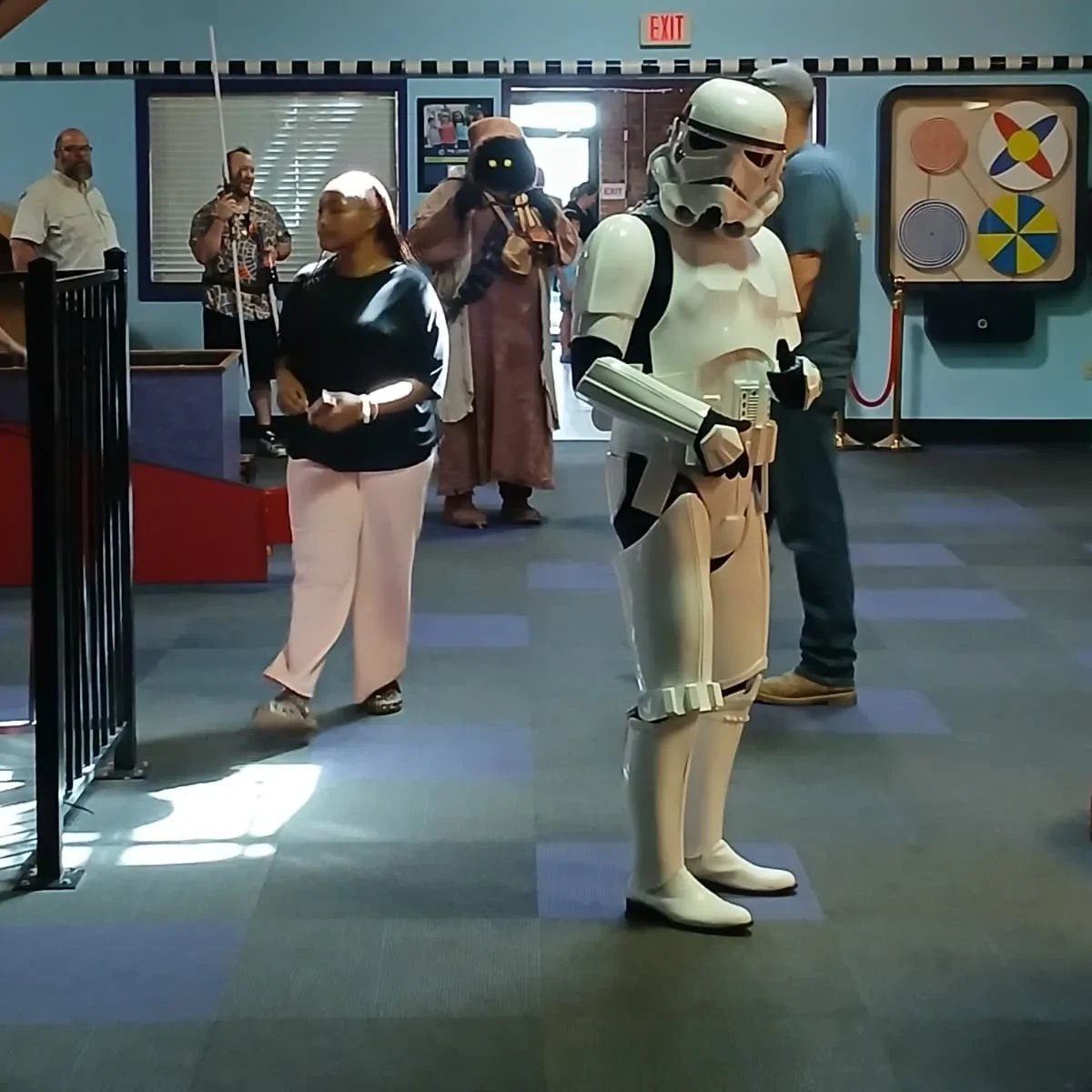 Stormtrooper from the 501st Legion standing in the lobby of the Northeast Louisiana Children's Museum with a Jawa visible in the background