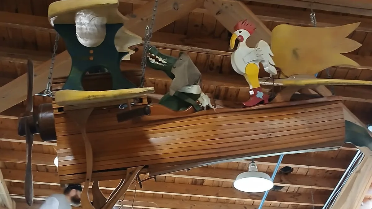 Large wooden airplane model with animal figures hanging from the ceiling beams inside the Northeast Louisiana Children's Museum in Monroe